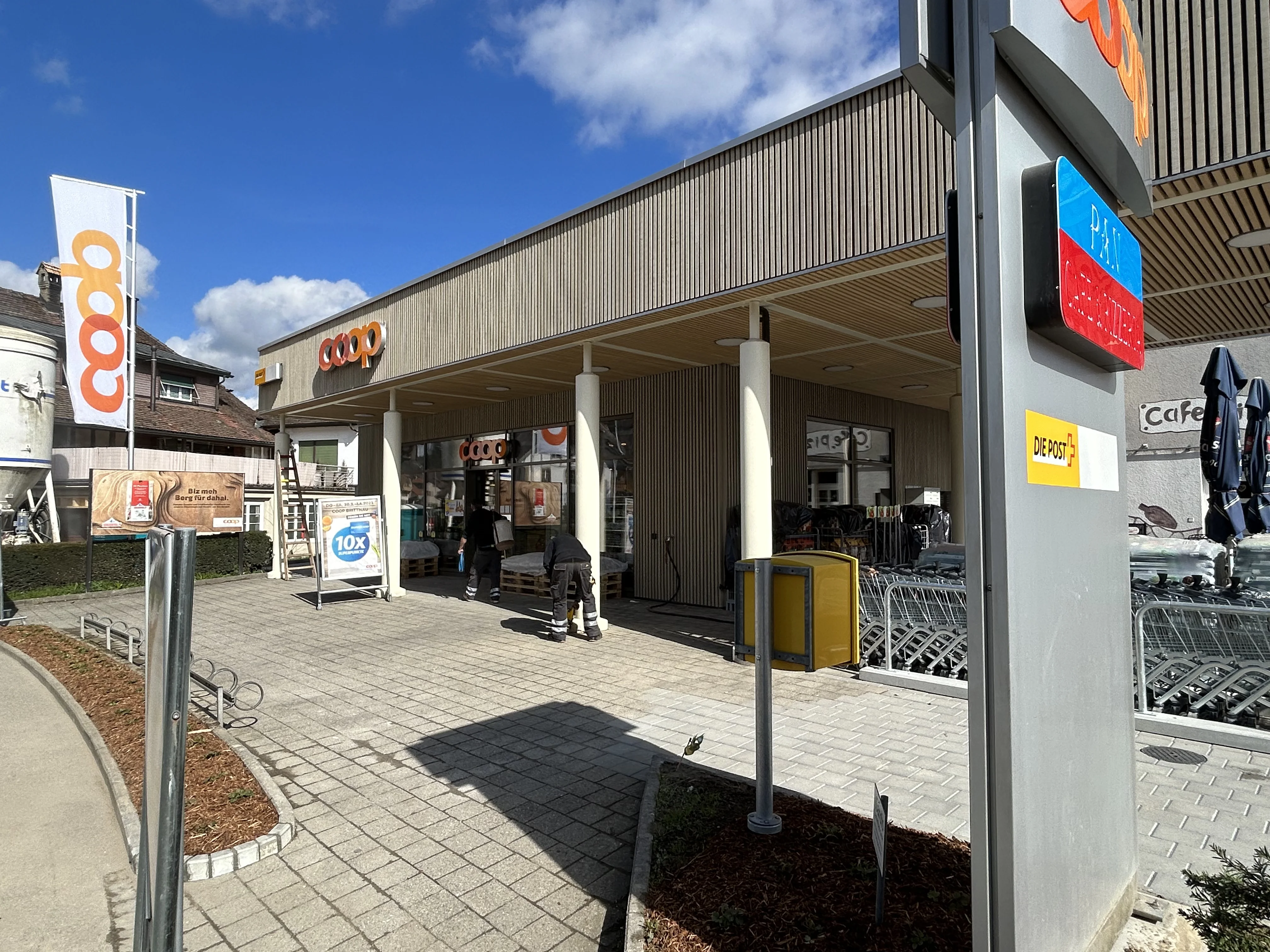 Kundenzugang des Coop Brittnau mit neuer Holzfassade und Vorplatz.