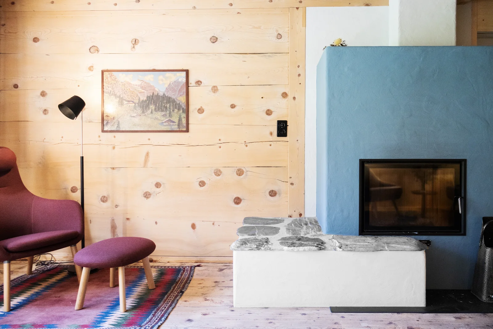 Der blaue Ofen setzt einen Akzent zwischen Holz und Sitzmöbeln